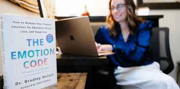 the emotion code book along with a woman working at the computer