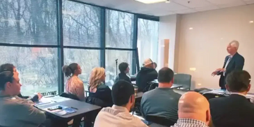 A group of people listening to a guest speaker at a seminar.