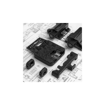 Carbon fiber mechanical parts arranged on technical blueprint paper.
