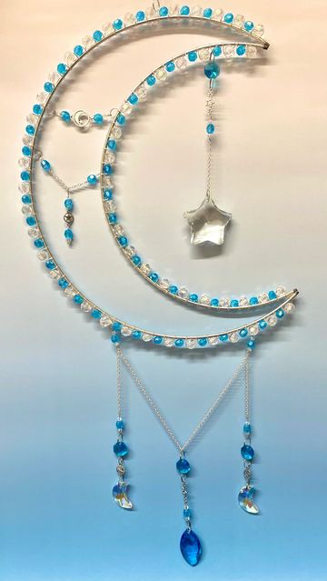 Decorative crescent moon with blue beads and hanging star and pendants.