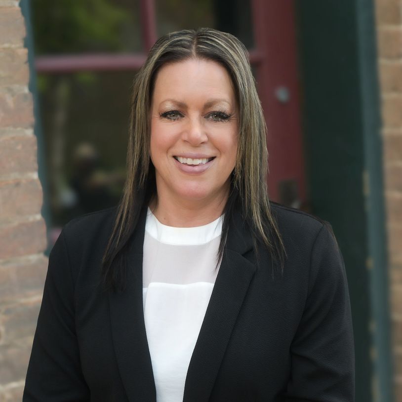 Smiling woman in business attire standing outdoors.