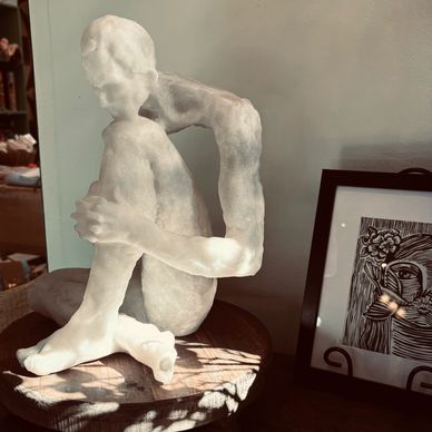 Abstract translucent sculpture of a seated figure with elongated limbs.