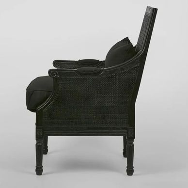 Side view of a black wicker armchair with cushions.