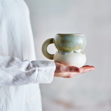 Person holding a uniquely designed ceramic mug with two rounded sections.