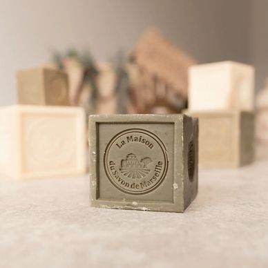 Square soaps with embossed French text on a neutral surface.