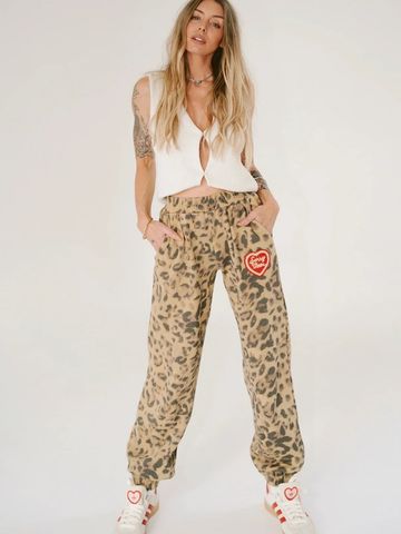 Woman wearing leopard print pants and a white sleeveless top.