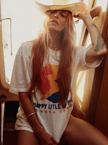 Woman with long hair wearing a cowboy hat and a graphic t-shirt.