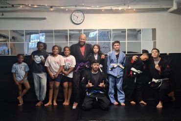 Martial arts group posing in a gym with a coach.