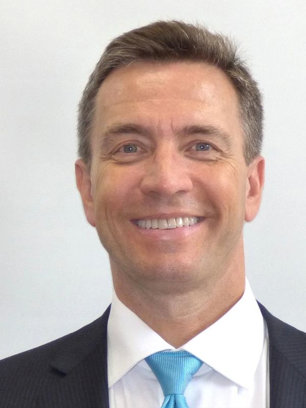 Smiling man in a suit and blue tie.
