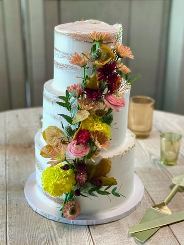 White and Rustic Fall Naked Wedding Cake with Real Flowers Cascading down the middle. 