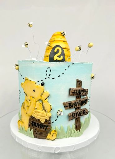 Pooh Bear Inspired Birthday cake with bee hive, bumble bees, and picket sign with "Happy Birthday"