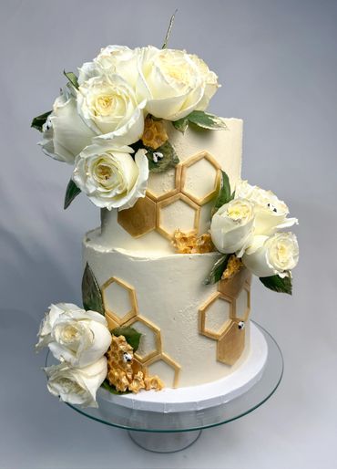 A little honey is on the way. Baby shower cake with honeycombs, and natural white roses cascading.