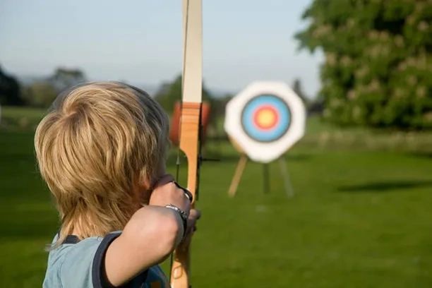 Kid pointing bow at target in the distance.
