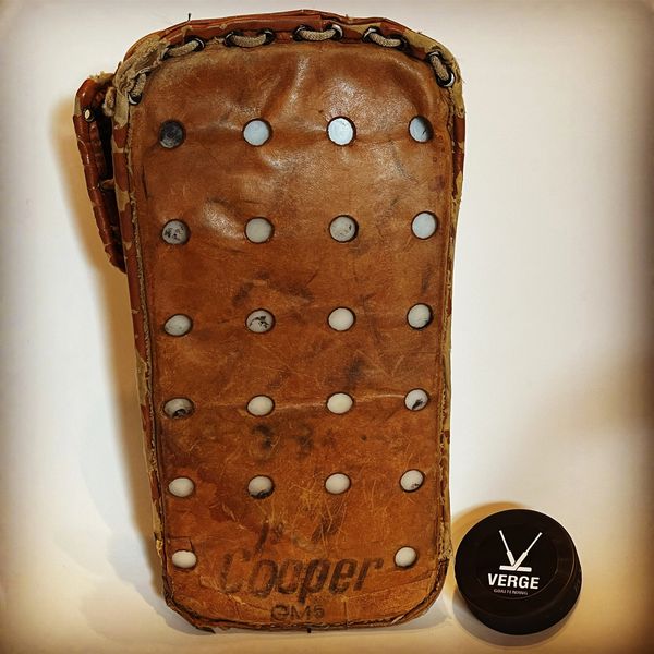 Vintage brown leather Cooper hockey goalie blocker with a modern Verge puck.