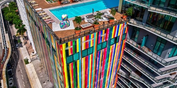 Colorful building with rooftop pool and plants.