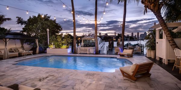 Evening poolside with city view and boats.