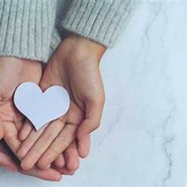 Two hands holding a paper heart symbolizing love and care.