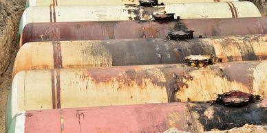 Old rusty fuel tanks partially buried in dirt.