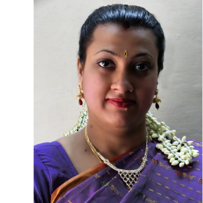 Woman in traditional purple saree with jasmine garland in hair.