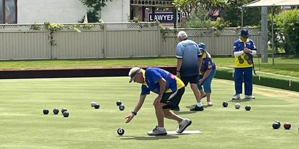 Seniors playing lawn bowls on a sunny day in a community park.