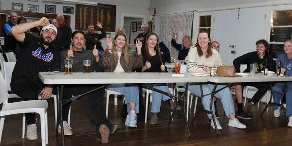 Group of people enjoying drinks and giving thumbs up at a social gathering.