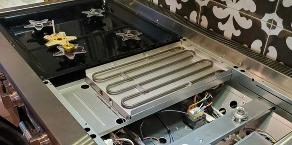 Open gas stove revealing its internal heating element and wiring.