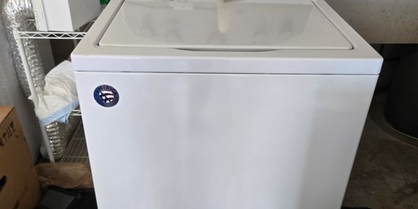 White top-loading washing machine in a garage.