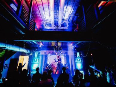 A lively concert with vibrant blue and purple lighting and an enthusiastic crowd.