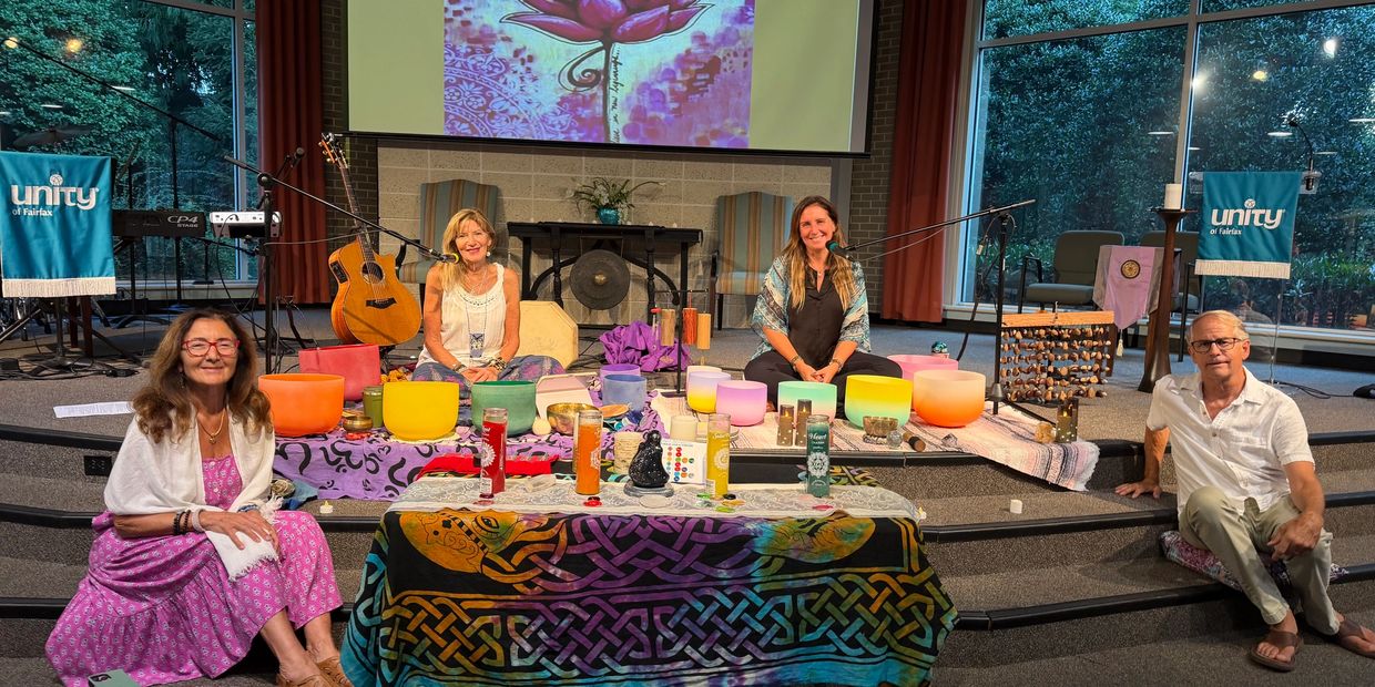 Four people sitting on steps with musical instruments and colorful art.