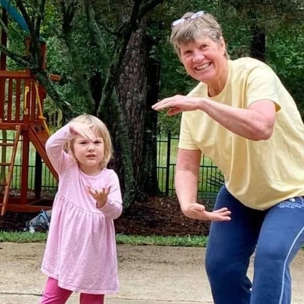 A woman and a young girl mimicking martial arts poses outdoors.