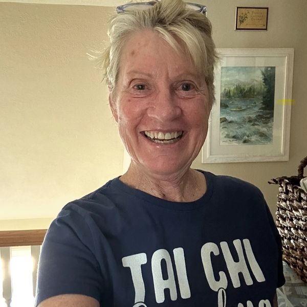 Smiling elderly woman wearing a Tai Chi Grandma shirt indoors.