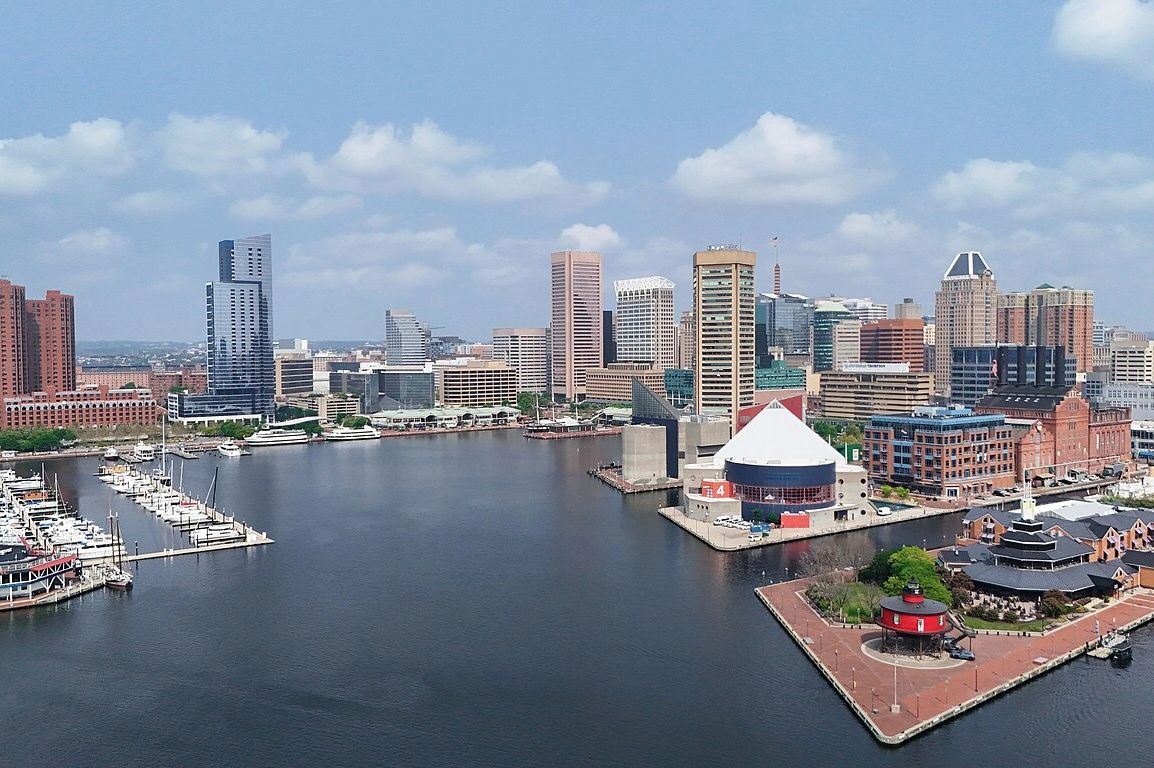 A city skyline with waterfront and boats docked at a marina.