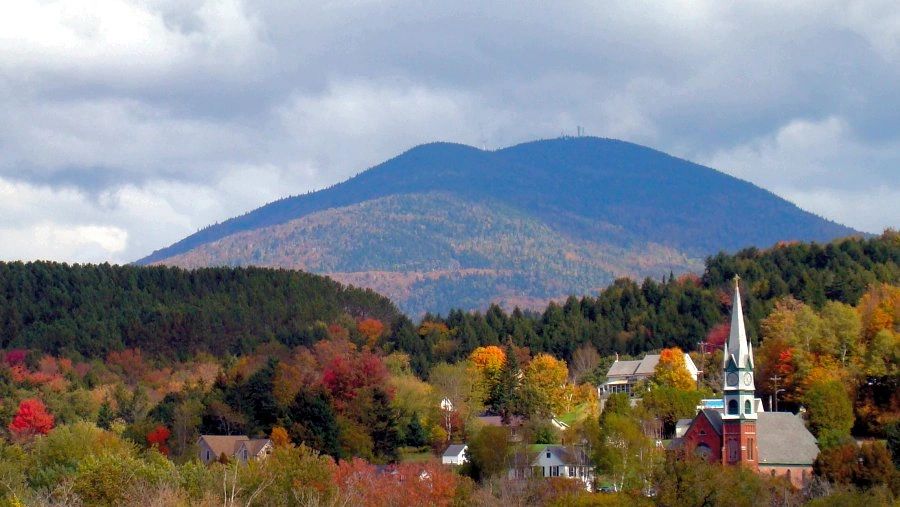 A picturesque village with colorful autumn trees and a mountain backdrop.