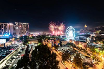 Night cityscape with fireworks and a brightly lit Ferris wheel.