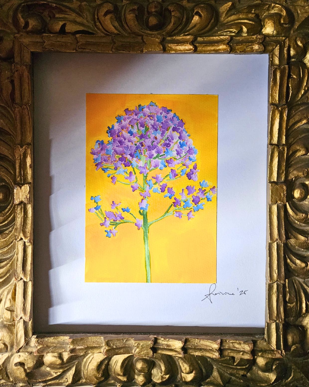 Cuadro de flor morada sobre fondo amarillo, en marco dorado.