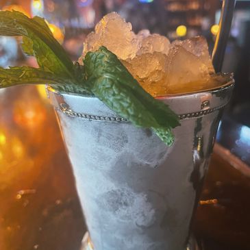 Mint julep in a frosty silver cup with crushed ice and fresh mint.
