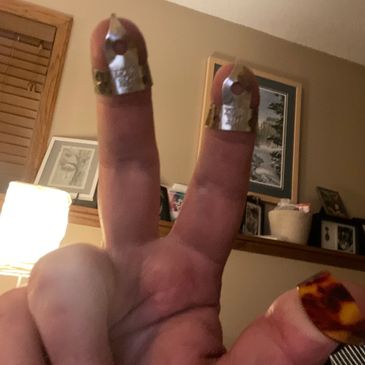 Fingers with metal thimbles and a guitar pick on the thumb.