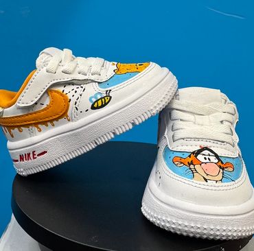 Custom white Nike sneakers with orange accents and cartoon bee and tiger designs.