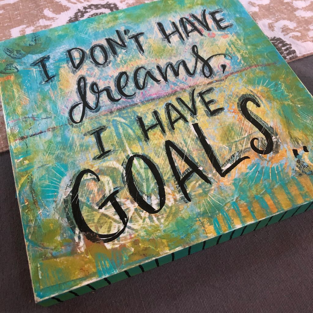 Artwork in  of aqua and yellow with handwritten words: "I DON'T HAVE dreams, I HAVE GOALS. 