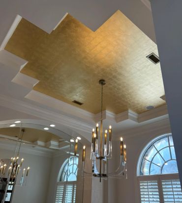 Gold-patterned ceiling with modern chandelier.