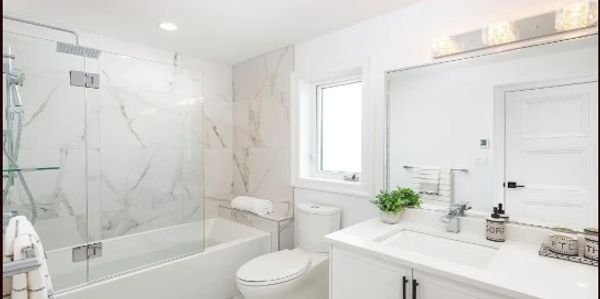 Bright modern bathroom with white fixtures and marble accents.