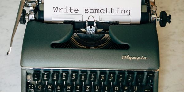 grey typewritter with a paper saying write something