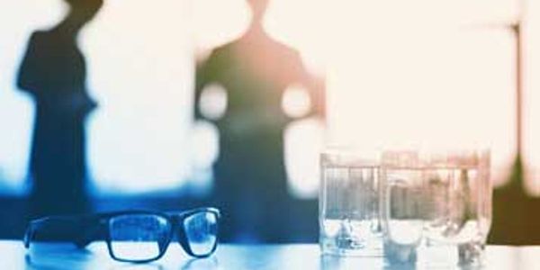 Glasses and water glasses on a table with blurred people in the background.