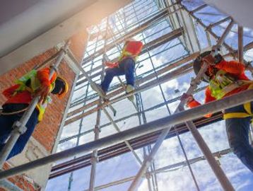 Construction workers installing large windows on a building with scaffolding.