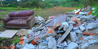 A discarded sofa next to a pile of rubble outdoors.