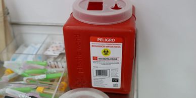Red biohazard container for sharp infectious waste in a medical setting.