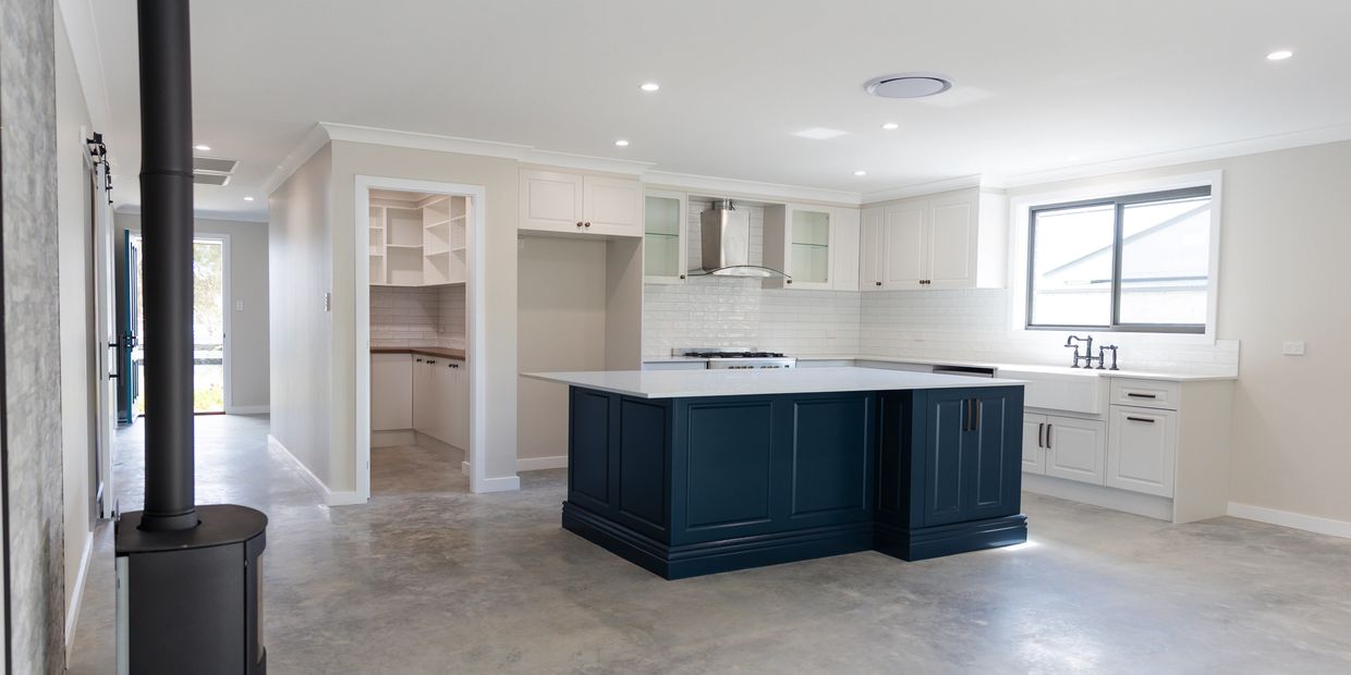 Burnished concrete floor with open plan living, A big blue kitchen island bench in a new build, Gilg
