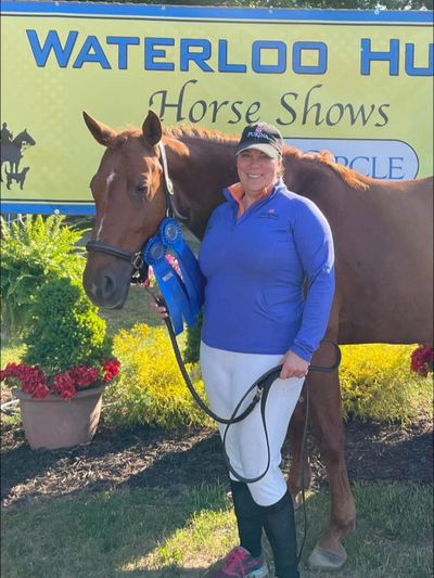 Woman with her horse and blue ribbons at a horse show event.