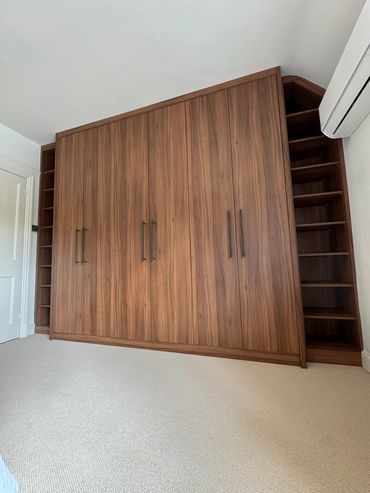 Large wooden wardrobe with side shelves in a bright room.
