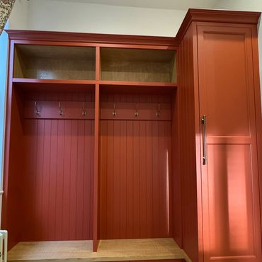 Rust-colored built-in bench with storage and hooks in a cozy entryway.